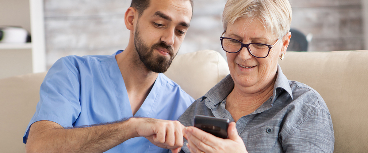 caregiver helping an elderly woman with her phone